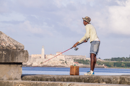 Havana, Cuba on December 22, 2016: Fisherman with rod on Malecon in front of Castillo de los Tres Reyes del Morroのeditorial素材