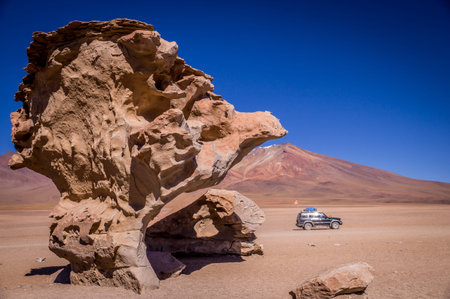 car driving past Arbol de Piedra rock formations, a popular stop on tours for tourists visiting Uyuni regionの写真素材