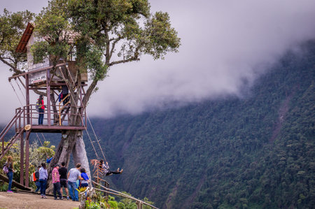 Banos, Ecuador on November 18, 2015: Tourists enjoying the giant swing at the treehouse Casa del Arbol in the Andes near Banos, Ecuador. The view from the swing is breathtaking.のeditorial素材