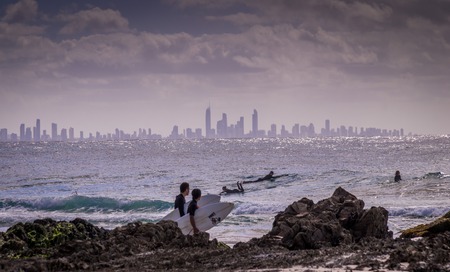 Surfers Paradise, Australia on August 16, 2016: Surfers enjoying the waves at snapper rocks with the skyline of Surfers paradise in the backgroundのeditorial素材