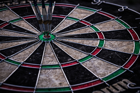 Three dart arrows hitting in the target center of dartboardの写真素材