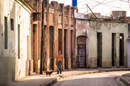 Man with dog walking in a street in Camagueys historic old townのeditorial素材