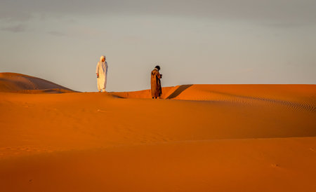 Merzouga, Morocco on February 24, 2018: Two Berbers wandering in Sahara desert, Merzouga, Moroccoのeditorial素材