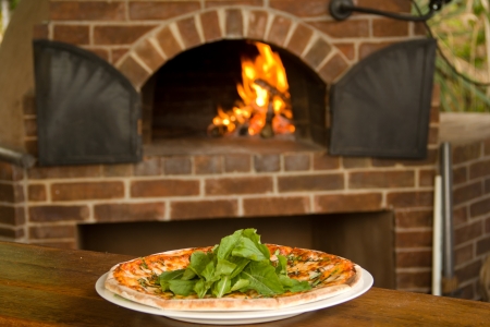 Pizza on a plate with pizza oven in backgroundの写真素材
