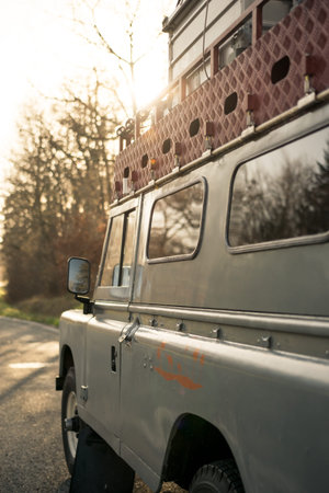 Side of an four by four oldtimer off-road vehicle at sunset with golden light and reflections in the windowの写真素材