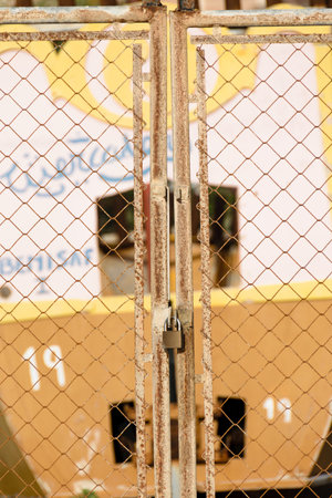 A rusty fence that is secured by a padlock.