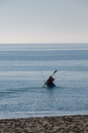 A canoeist with fishing rods paddling on the Mediterranean Sea on a beautiful sunny day with blue sky at the Costa Blanca in Spain.の写真素材