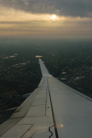 Aerial image taken from a plane where you can see the wingtip the sun and the earth.の写真素材