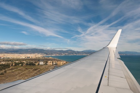 A beautiful aerial view over Malaga through the window of an aircraft with the wing in focus. The weather is beautiful with blue sky and some clouds.の写真素材