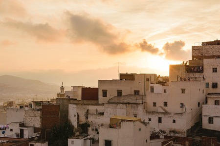 Close up of some old houses in the city of Tetouan in Morocco at sunset. The sky is golden and there are few clouds in the sky.の写真素材