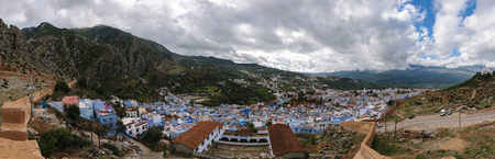 An awesome panoramic view over the blue painted and famous city Chefchaouen in Morocco. It is located in the Rif Mountains. The sky is cloudy.の写真素材