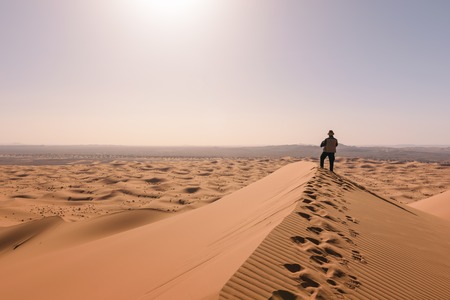 Man overlooks the dunes of Erg Chebbi, Merzouga, Moroccoの写真素材