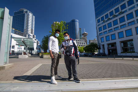 Vancouver, BC, Canada, May 8th, two men in medical masks in the empty Canada Place terminal, no cruise ships, no business, clean and quiet due to COVID19 quarantine 2020のeditorial素材