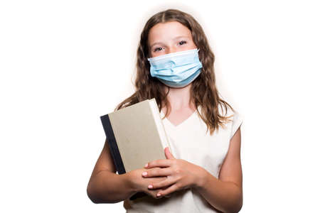 A portrait of a teenage Caucasian girl smiling, in the face cover, a mask, holding a book, isolated on the white backgroundの写真素材