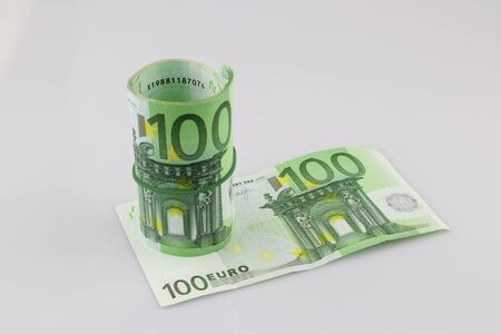 Roll of one hundred euro banknotes with a rubber band, isolated backgroundの写真素材