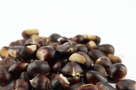 A handful of edible chestnuts separated on a white background. Isolated white background and autumn forest edible brown chestnuts.の写真素材