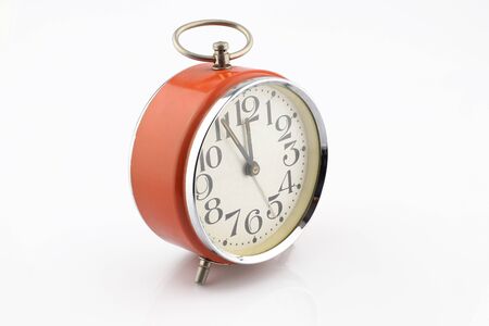 Old orange alarm clock separated on white background. Five minutes to twelve. Analog clock.の写真素材
