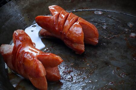 Two grilled sausages on hot dish (pan) during a summer barbecue ready to eat.の写真素材