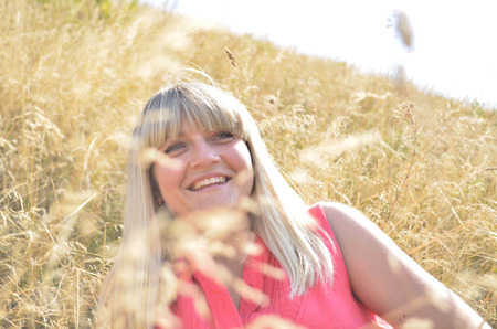 Young girl smiling on summer field under the sunの写真素材