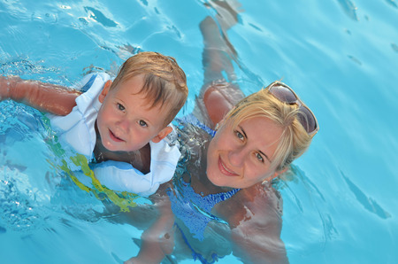 Young woman with her child are swimming in poolの写真素材