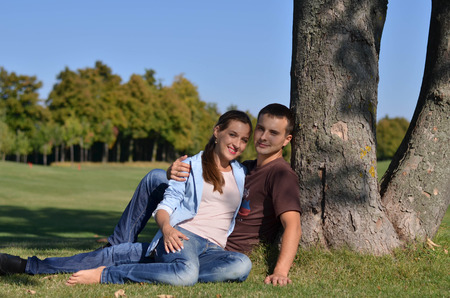 Young couple sittting under the tree in the parklandの写真素材
