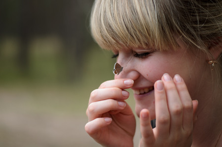 Young beautifull girl with small butterfly on her girl faceの写真素材