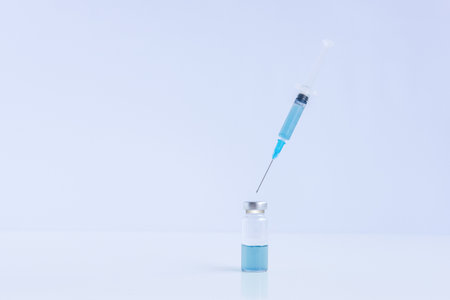 On white isolated background, transparent, glass vial with blue vaccine against viruses with disposable syringe. Fight against infection epidemics. Coronovirus pandemic. Injection, flu shot. Mock upの写真素材
