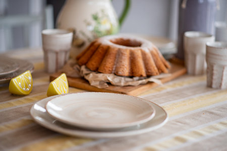Easter lemon bundt cake, Babka sprinkled with powdered sugar on a festive table decorated with ceramic dishes. Rustic, Scandinavian style in table setting for a holiday, gray yellow linen tableclothの写真素材