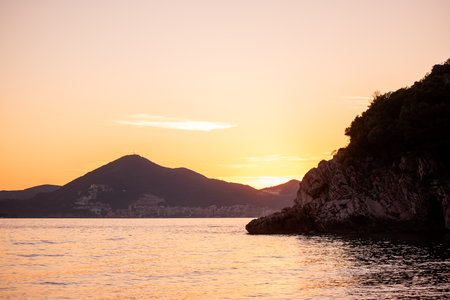 Rocky seashore, beach with green pine trees at sunset. Nature of Montenegro. Natural, texture background. Turquoise calm Adriatic Sea. Green coniferous forest. Scenic seascape. Wallpaper, copy spaceの写真素材