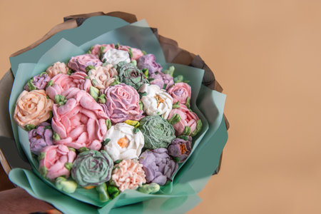 Festive bouquet of sweet sugar marshmallow rose flowers on beige isolated white background. Mockup place for text. Edible flowers, small business, hobby. Delicious holiday gift. Natural organic bakingの写真素材