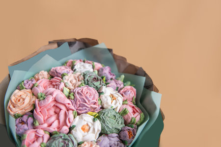 Festive bouquet of sweet sugar marshmallow rose flowers on beige isolated white background. Mockup place for text. Edible flowers, small business, hobby. Delicious holiday gift. Natural organic bakingの写真素材