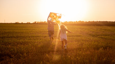Bald father in glasses runs around the field with daughter putting into the sky kite. Millennial man plays with girl in rural areas. Traveling, fun on the day of the father. Warm happy family memoriesの写真素材
