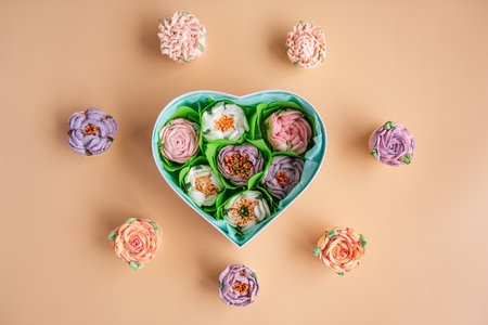 On orange isolated background lies gift box heart shape with sweet marshmallow flowers. Hand natural work. Dessert without sugar dessert peonies roses aster. Hobby, small business. Mock up, copy spaceの写真素材