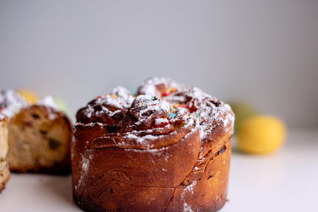 Easter Kraffin on a light background with colored, bright eggs. Cake with candied fruits, raisins,...
