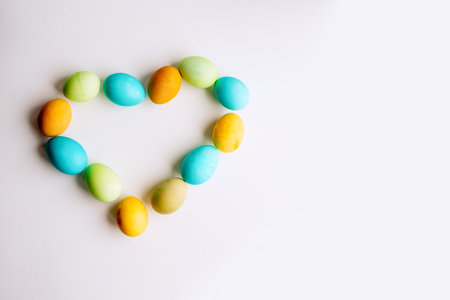 Easter bright, colored eggs in the shape of a heart lie on an isolated white background. The concept of kindness, faith in the holiday. Greeting card with place for text. Copy space, mock upの写真素材