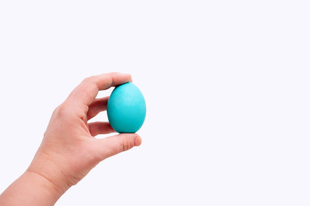 Human hand holds blue Easter egg on an isolated white background. Place for text. Mock up, copy space. Minimalismの写真素材