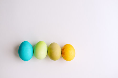 Easter bright, blue, green, orange eggs lie in a row on an isolated white background. Greeting card with place for text. Copy space, mock upの写真素材