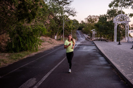 Young woman in sportswear runs along the path at dawn. Morning routine, meditation, feeling of...