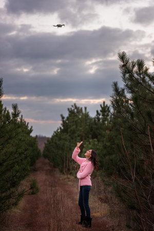 Young woman in knitted pink in the countryside among coniferous trees in the forest posing for a...