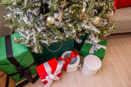 Close-up of a decorated Christmas tree with various wrapped gifts in vibrant colors placed underneath on a wooden floor.の写真素材