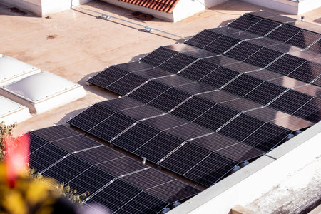 Rows of solar panels installed on a flat rooftop, capturing sunlight for renewable energy in an...