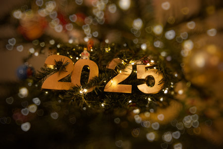 Horizontal Golden 2025 with bokeh ornament on a decorated Christmas tree, illuminated by warm string lights, symbolizing festive New Year celebrations and holiday joy. Authentic card, lifestyleの写真素材