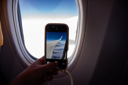 Passenger capturing a stunning photo of the airplane wing through the window during a flight,...