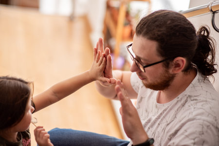 Father and little daughter sharing a joyful high five at home, enjoying playful moments together...