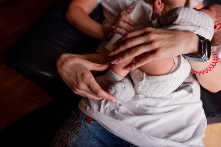 Nurturing moment captured as a parent lovingly cradles a newborn baby. The gentle embrace conveys warmth, comfort, and the tender bond between parent and childの写真素材