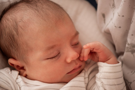 Serene newborn baby peacefully sleeping, dressed in a cozy striped outfit. The infant's gentle expression and delicate features capture the essence of calm and innocenceの写真素材
