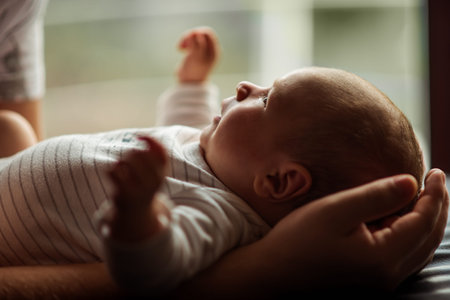Newborn baby rests peacefully in an adult's arms, capturing a tender moment of care and connection....