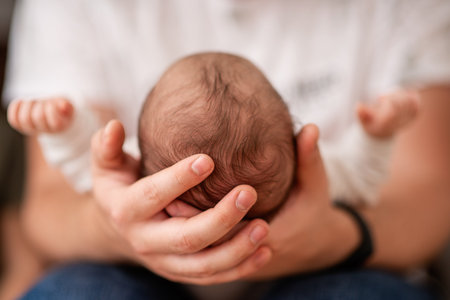 Close-up capturing a parent gently cradling a newborn's head, emphasizing the tender bond and deep love shared in a soft, intimate atmosphere filled with warmth and securityの写真素材
