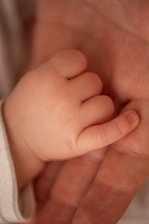 Close-up of a newborn baby's tiny hand gently grasping an adult's finger, capturing the essence of love, connection, and the beautiful journey of new life unfoldingの写真素材