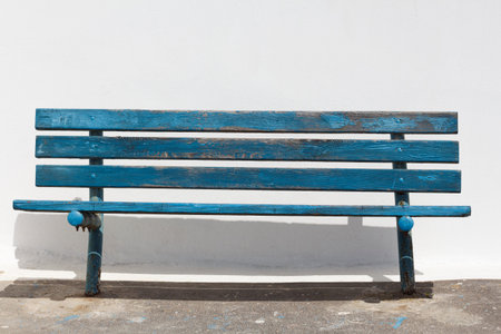 Blue bench on a background of white wall. Front view